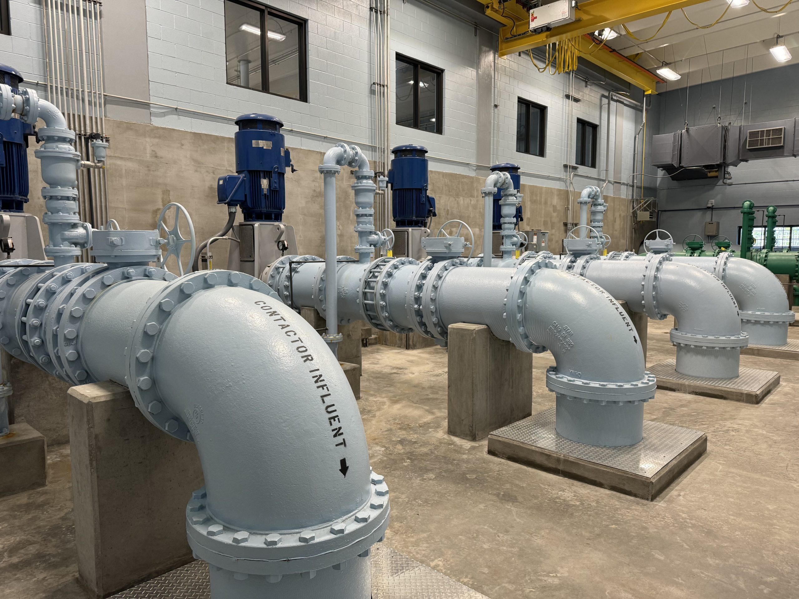 Image of large industrial pipes bolted a concrete floor. the pipes send water to filtration pools where contaminants are removed.