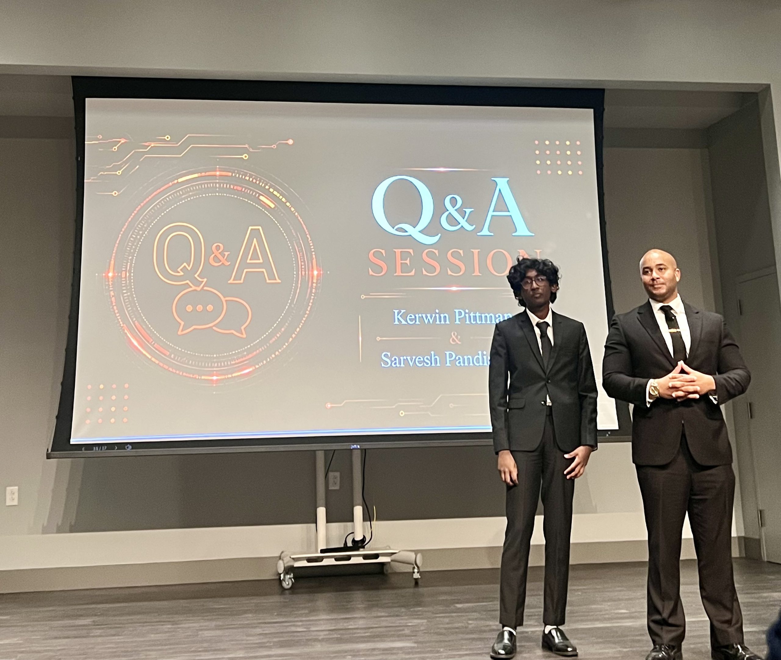Two men in suits stand answering audience questions about a new reentry app