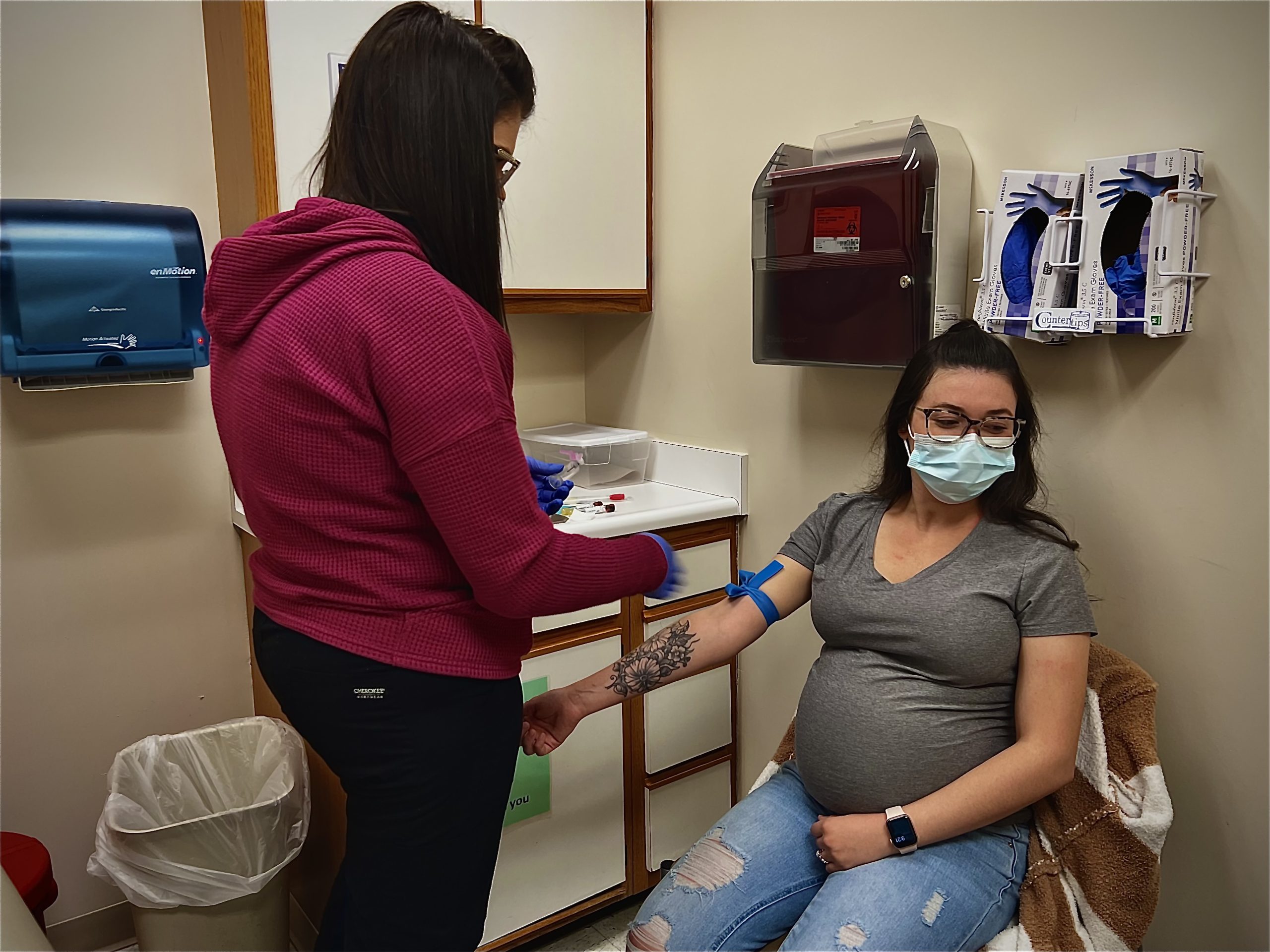 a woman draws blood from a pregnant patient who will have to travel to a different county to give birth because there is no longer a labor and delivery unit in the city