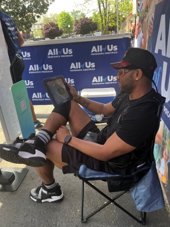 A black man seated in a chair holds an iPad