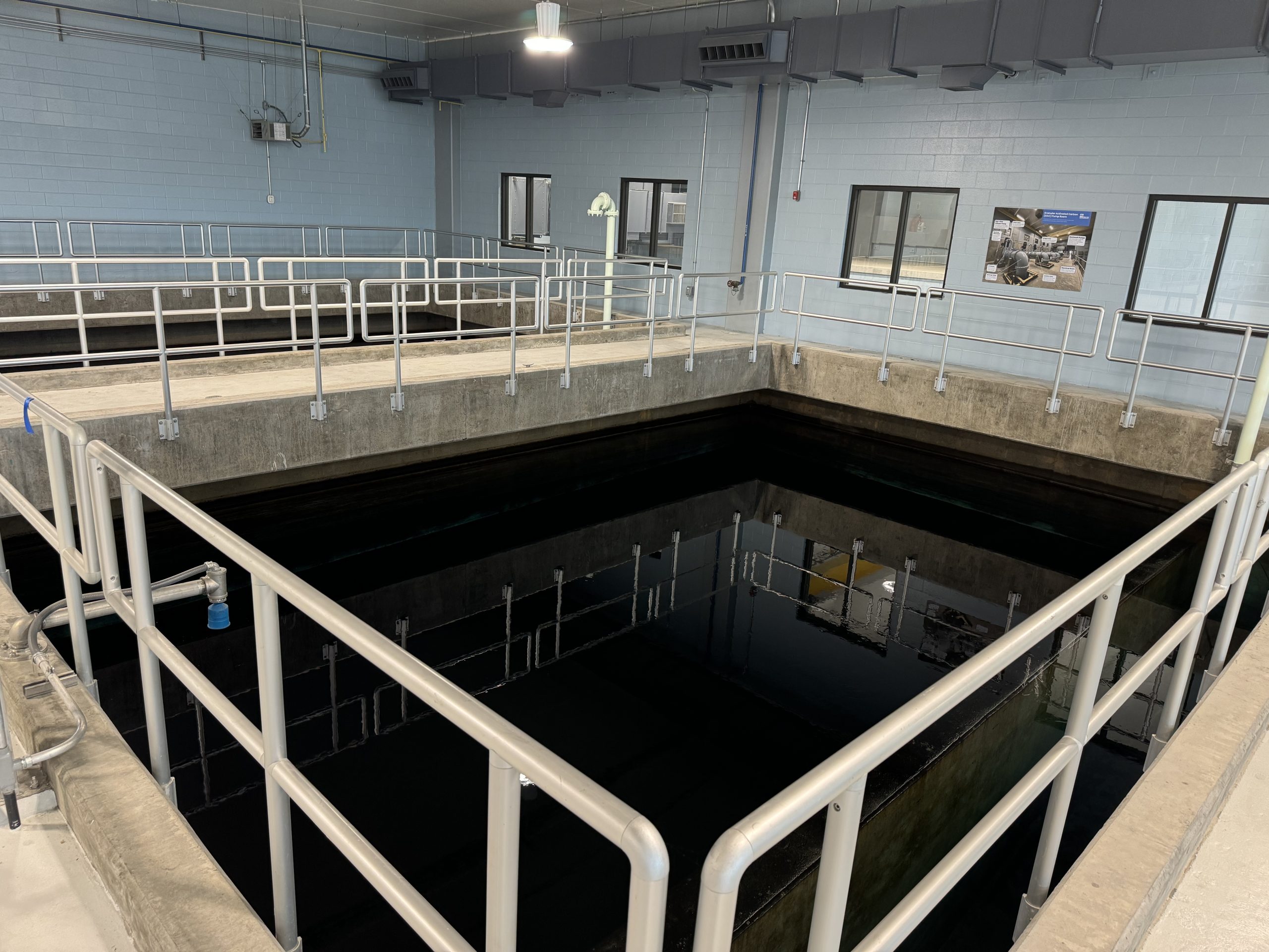 The image of a poolf water that is contained in a concrete basin and surrounded by metal guard rails.