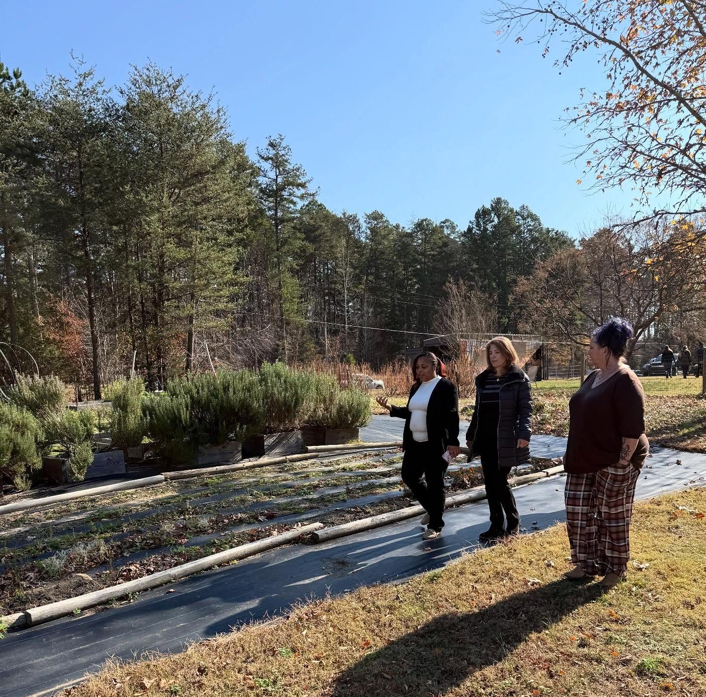 Three women — one the first lady of North Carolina and the others formerly incarcerated women — walk along a farm that serves as a reentry program