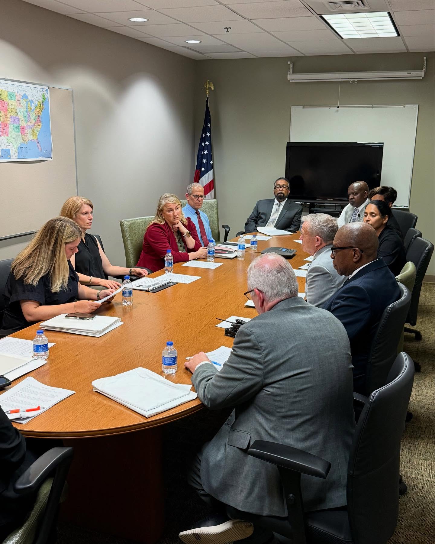 Many people in suits sit around a round table discussing prison reentry options