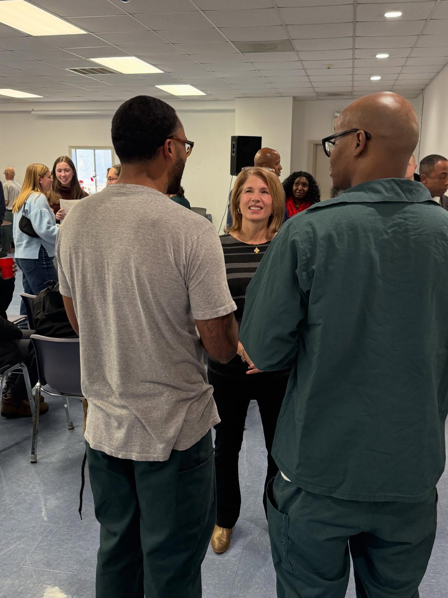 The first lady of North Carolina talks with two incarcerated men in green jumpsuits