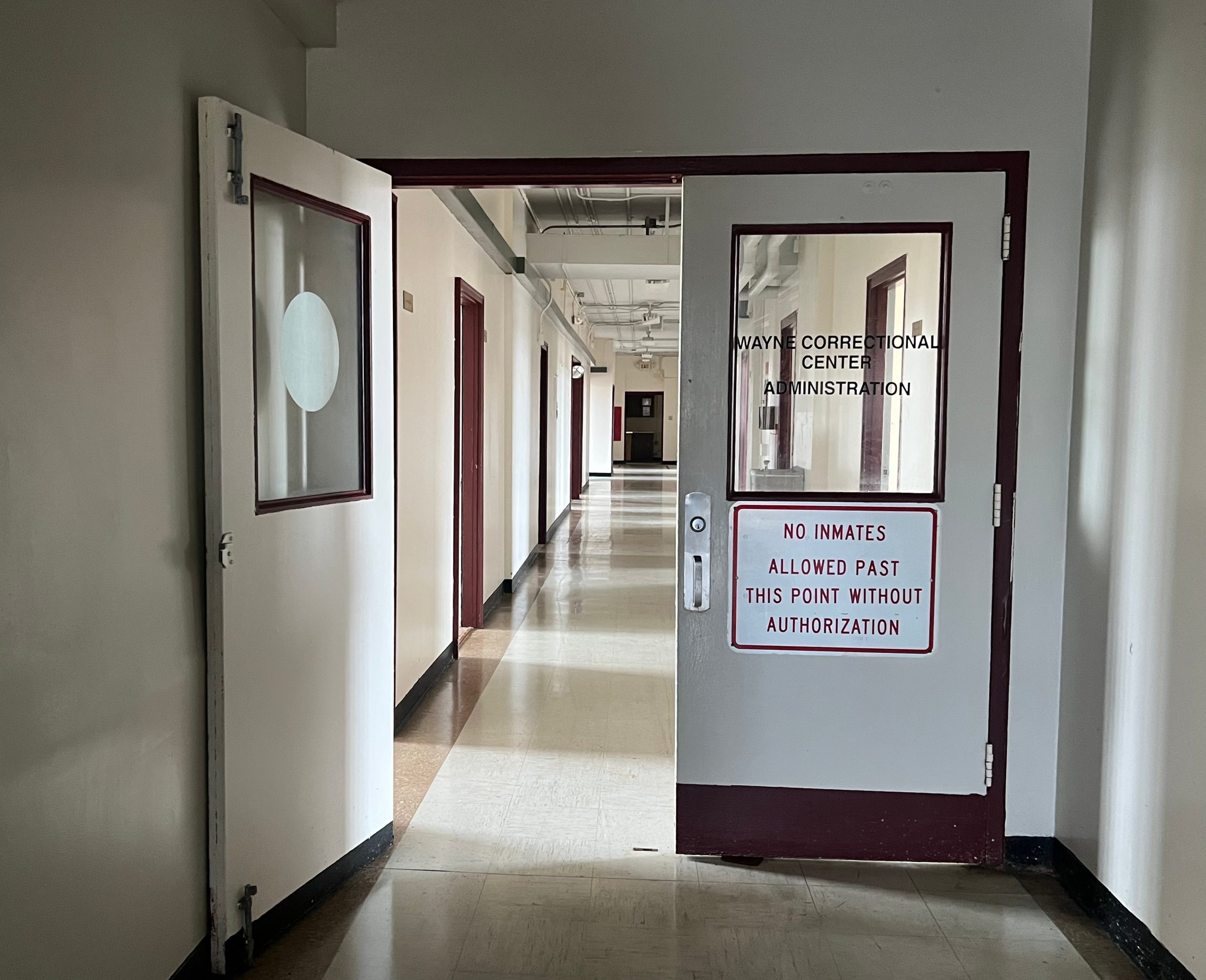 An open door leading down a hallway with a sign reading,