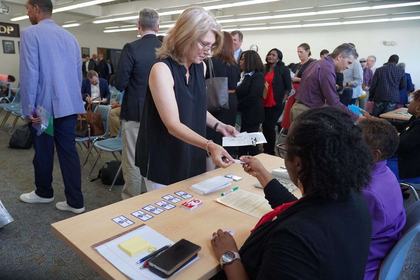 A woman hands over a ticket while stopping at a station during a reentry simulation aimed at showing participants the challenges of life after incarceration
