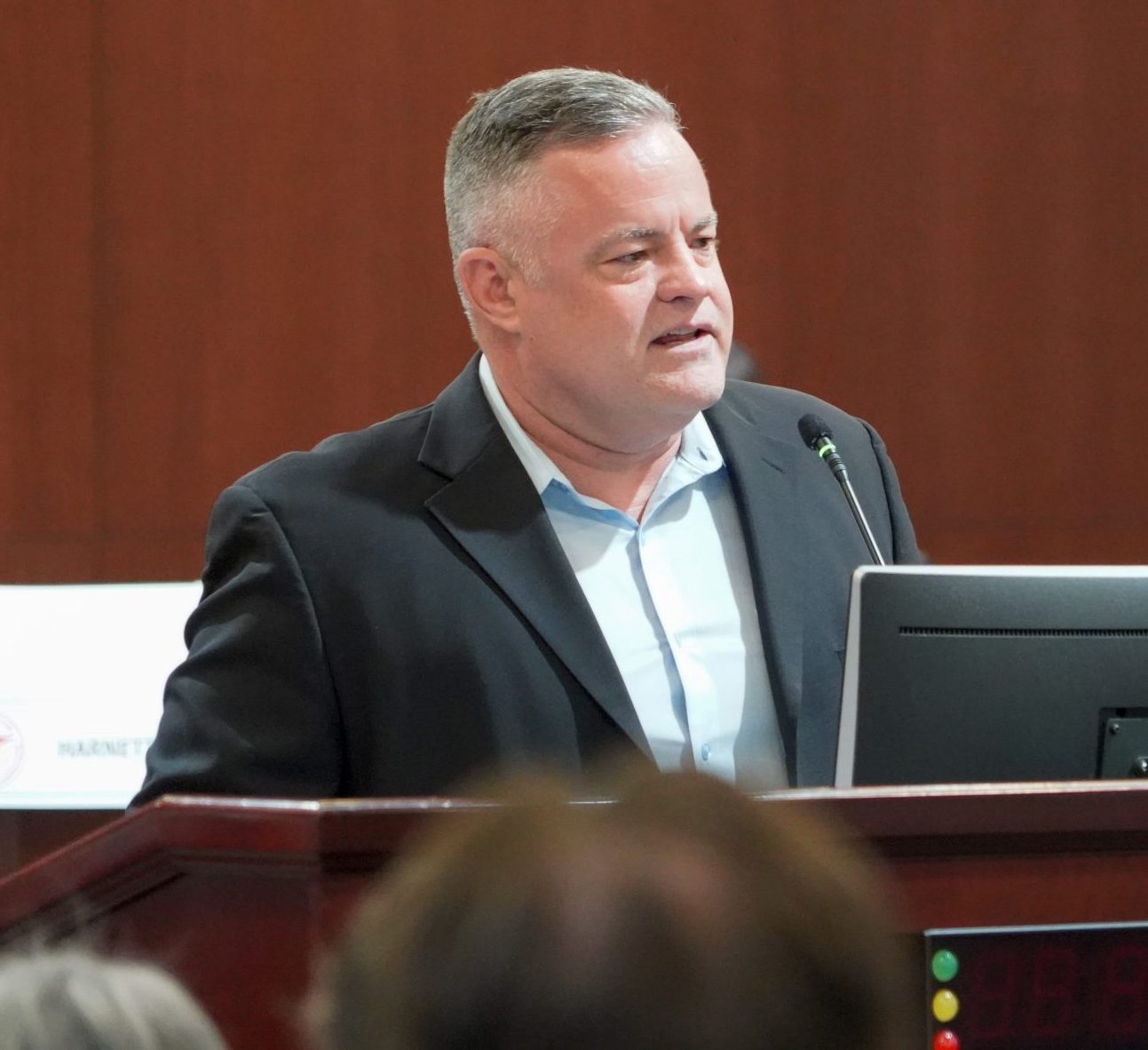 A white man in a suit who is a former law enforcement officer stands at a podium talking about law enforcement assisted diversion