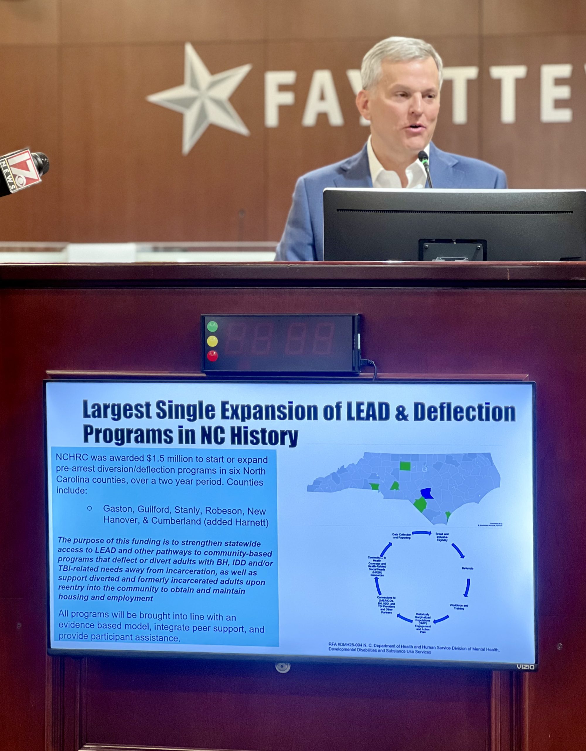 A white man stands at a podium talking about North Carolina's largest expansion of Law Enforcement Assisted Diversion program