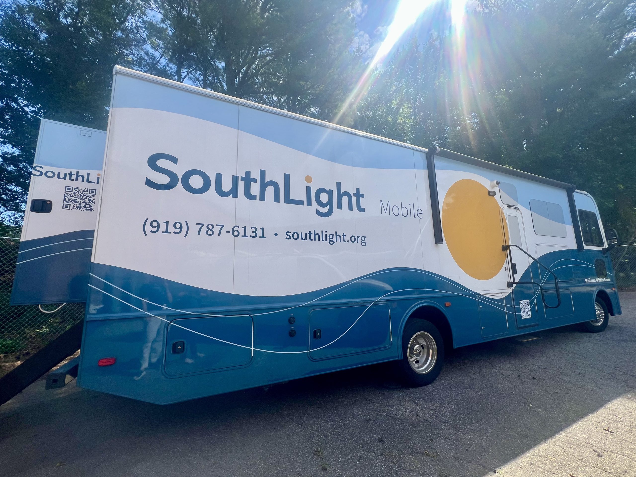 A blue and white mobile opioid treatment program operated by SouthLight Healthcare. It's parked in a lot.
