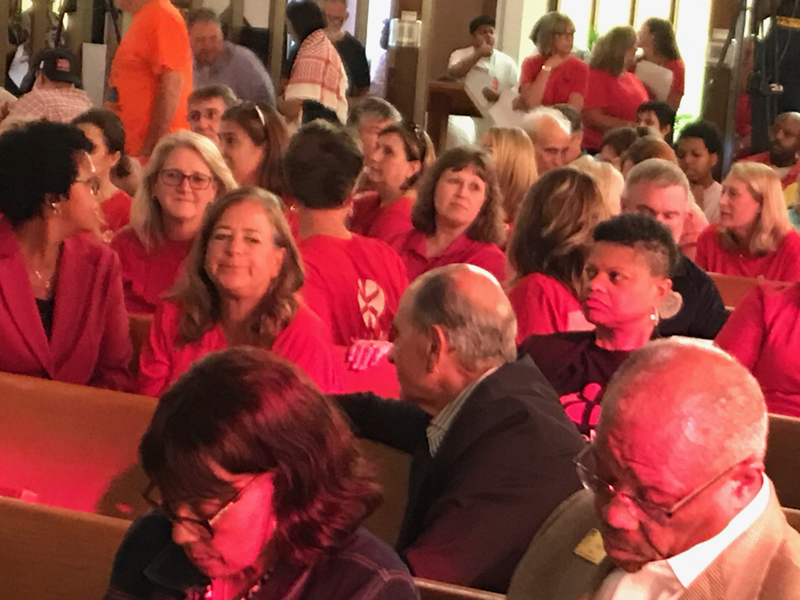 WakeMed advocates wearing red t-shirts filled pews at St. Ambrose Episcopal Church in Raleigh for a town Hall on WakeMed, Atrium Health partnership