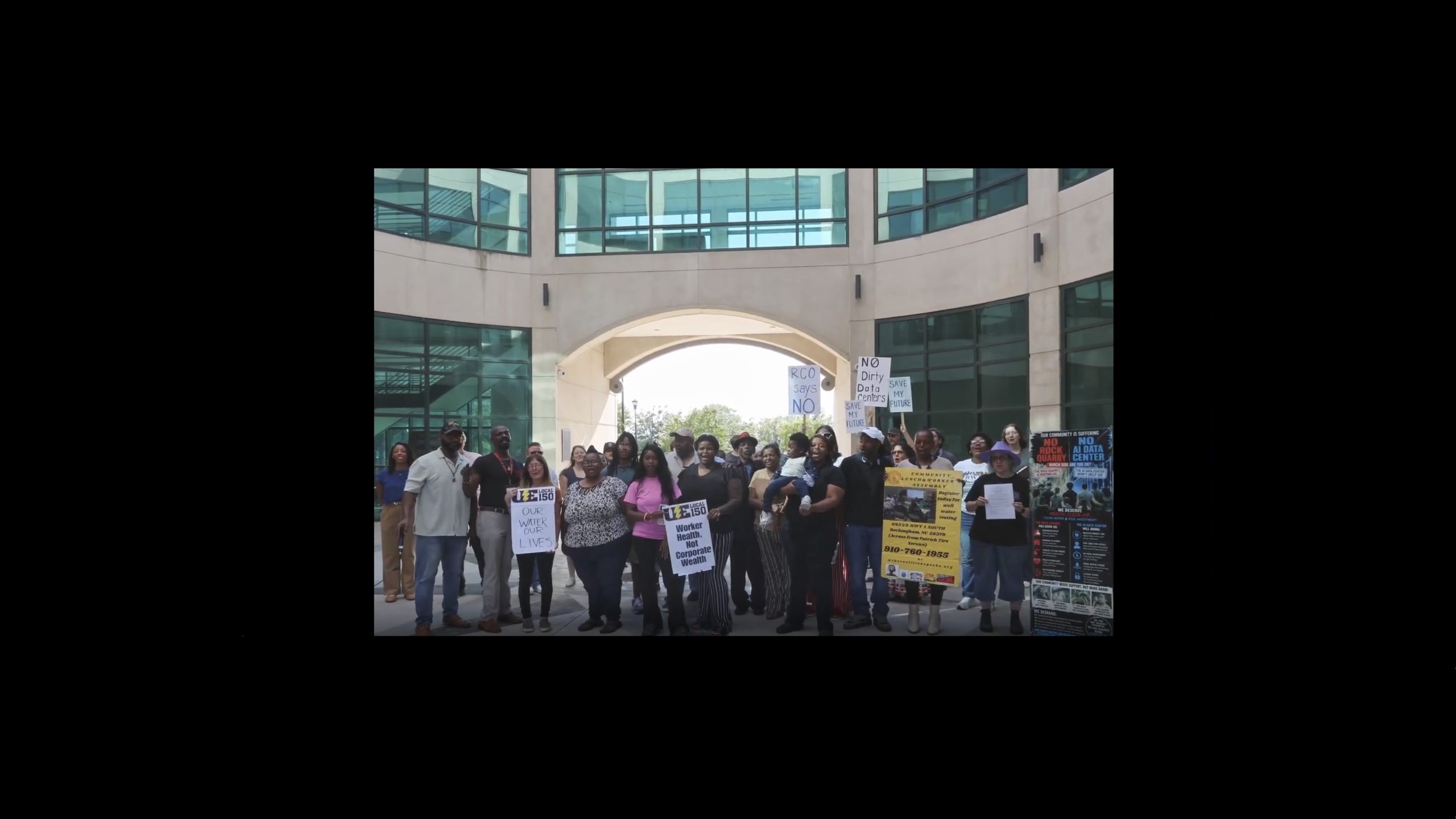 A group of Richmond County residents and advocates stands outside the Old Richmond County Courthouse in Rockingham after a press conference, holding signs opposing a proposed data center and raising concerns about water, health and pollution.