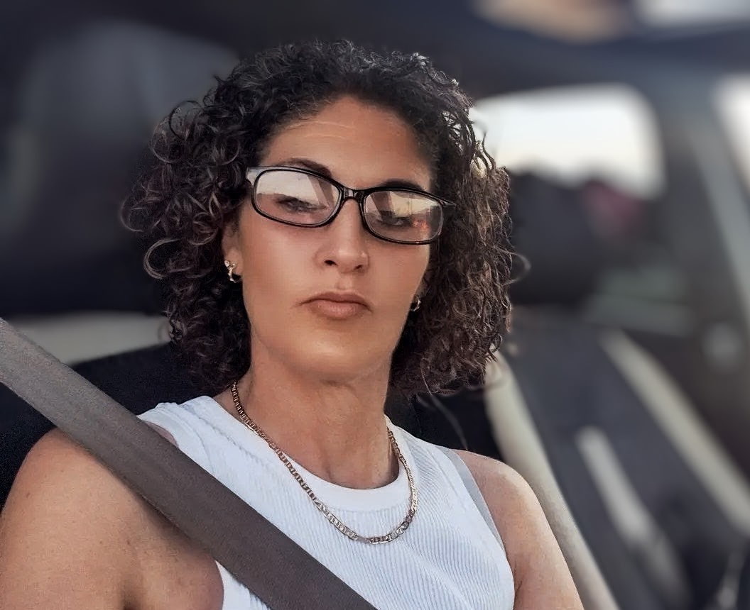 A woman in glasses takes a selfie in a car