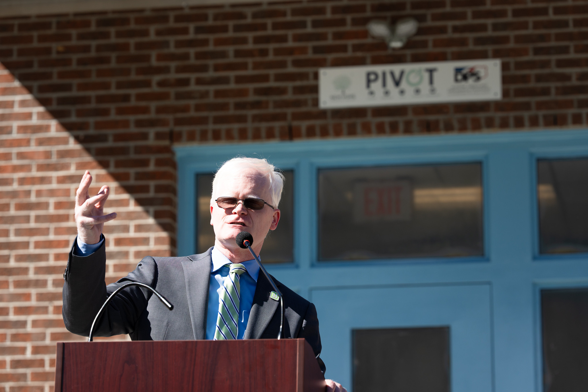 A man with white hair wearing a suit stands at a podium outside the juvenile justice system's new mental health unit